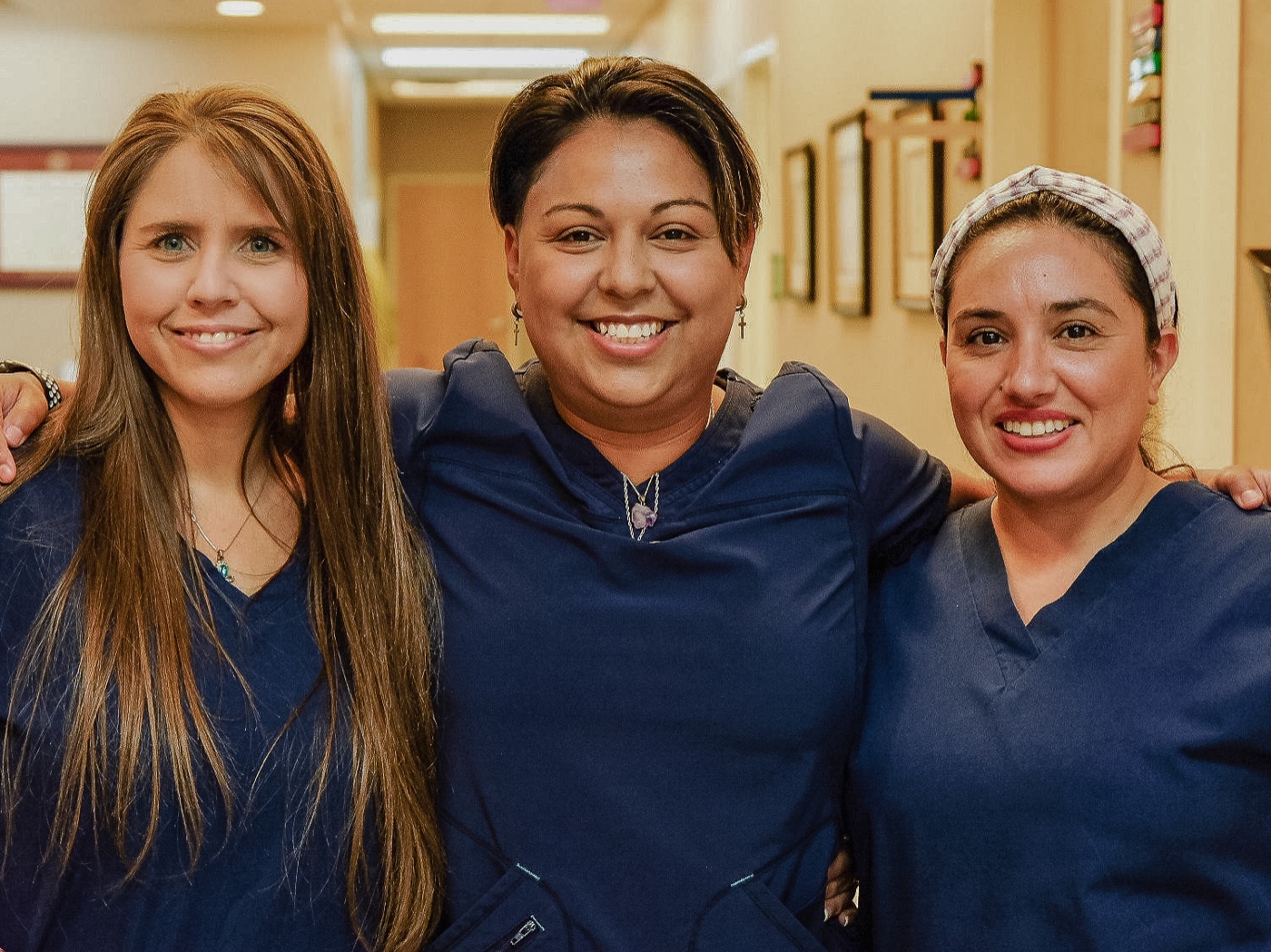 Three members of our staff smiling together in the clinic hallway